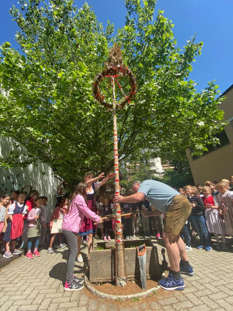 Alina schneidet mit Schulwart Bernhard Baumgartner den Maibaum um.