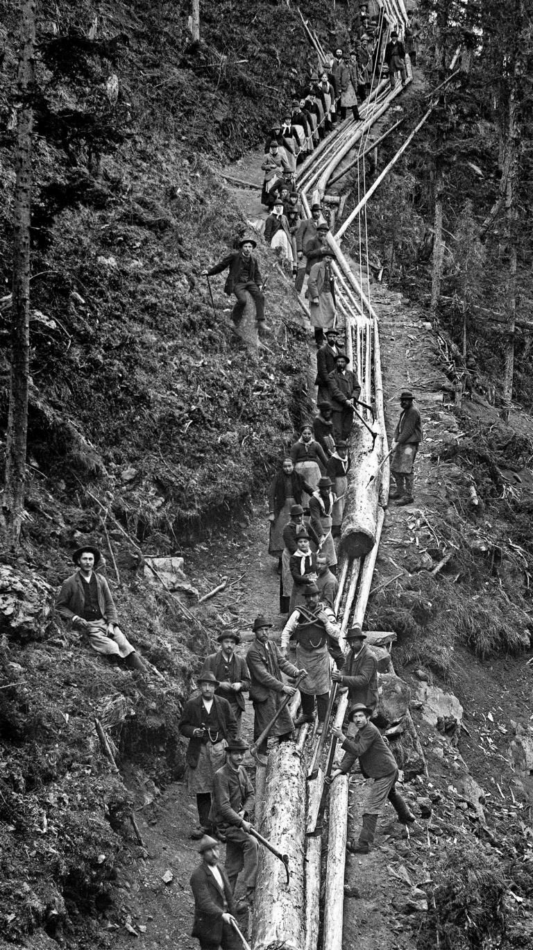 Ausstellungsschwerpunkt &bdquo;Technik&ldquo;: &Auml;u&szlig;erst gef&auml;hrlicher Holzst&auml;mme-Transport durch M&auml;nner und Frauen (!) in einer angelegten Riese oder Loite im Defereggental, um 1900 &ndash; in Pose f&uuml;r den Fotografen. Fotograf: Josef Ladst&auml;tter; Sammlung Heinz Kr&ouml;ll &ndash; TAP