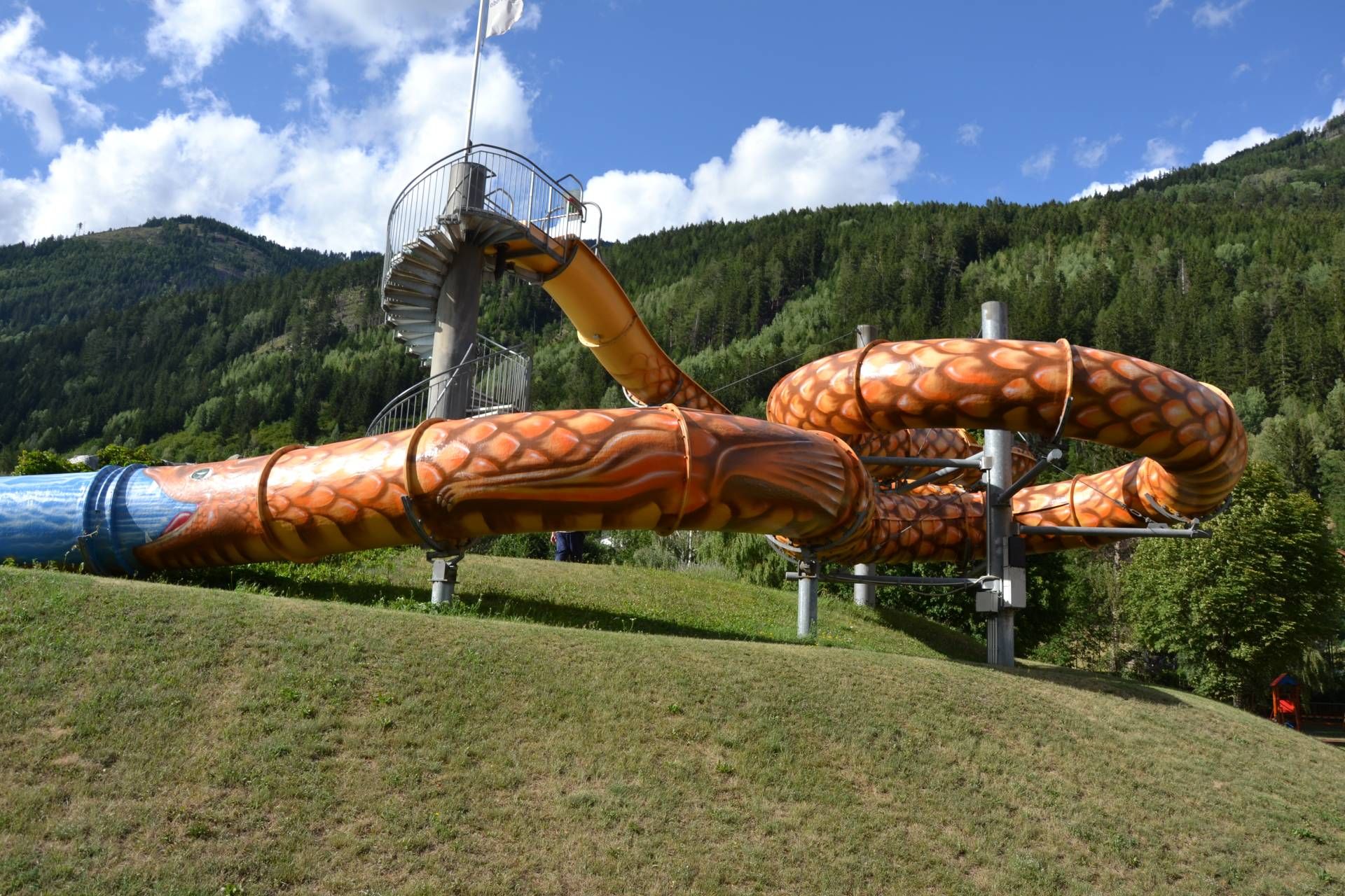 Der heimische K&uuml;nstler Gottfried Recnik verwandelte mit gez&auml;hlten 1.141 Schuppen die Rutsche im Obervellacher Freibad in einen riesigen Lindwurm, inspiriert von der alten Sage des Mallnitzer Lindwurms.